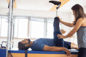 Kobieta wykonuje ćwiczenie Pilatesa z mężczyzną na podłodze.