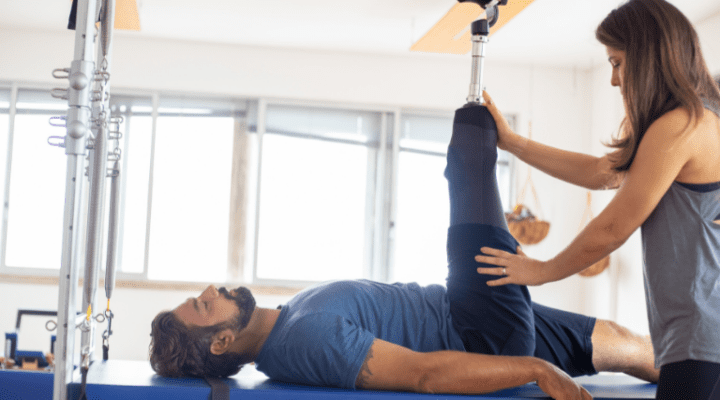 Kobieta wykonuje ćwiczenie Pilatesa z mężczyzną na podłodze.