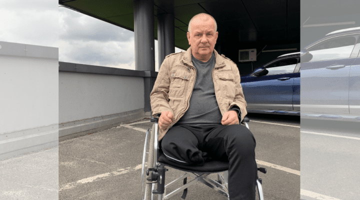 Mężczyzna na wózku inwalidzkim siedzącym przed samochodem.