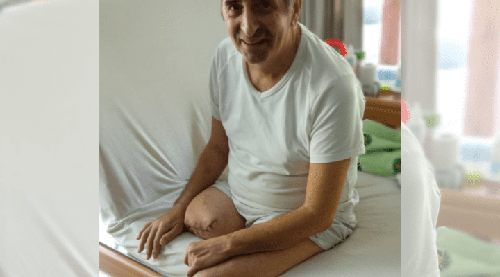 Mężczyzna siedzący na łóżku w pokoju szpitalnym.