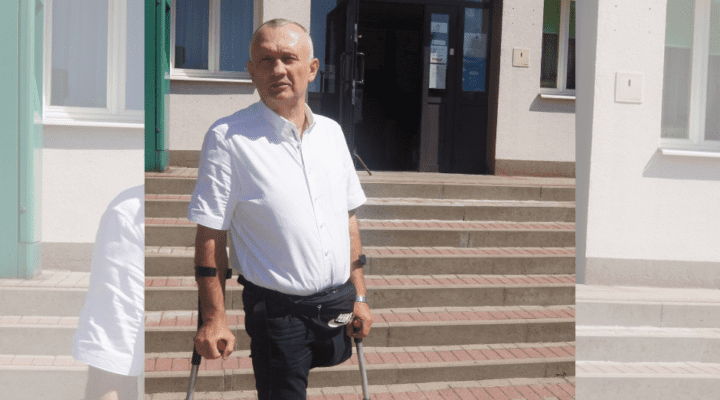 Mężczyzna o kulach stojących przed budynkiem.