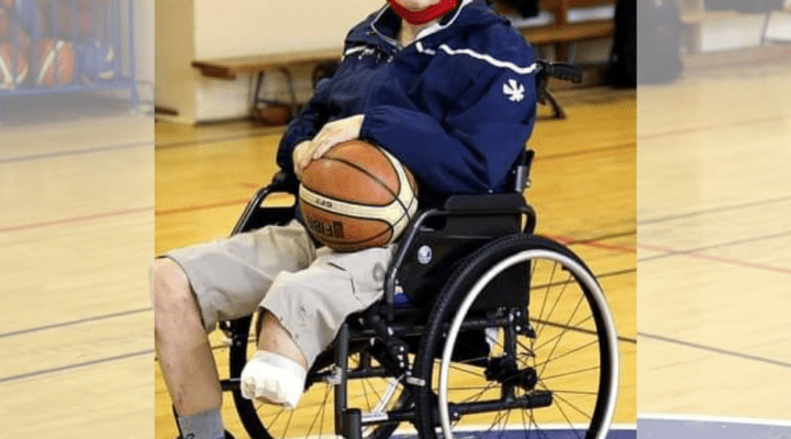 Starszy mężczyzna na wózku inwalidzkim trzymającym piłkę do koszykówki.