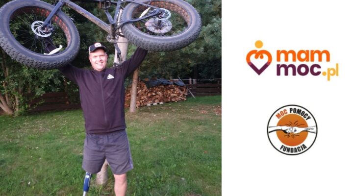 Mężczyzna trzymający rower ze słowami mamo Moc.