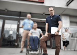 Mężczyzna siedzący na wózku inwalidzkim poza budynkiem.