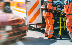 Grupa ludzi w pomarańczowych mundurach stojących w pobliżu karetki.