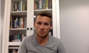 Mężczyzna siedzi przed półką książki.