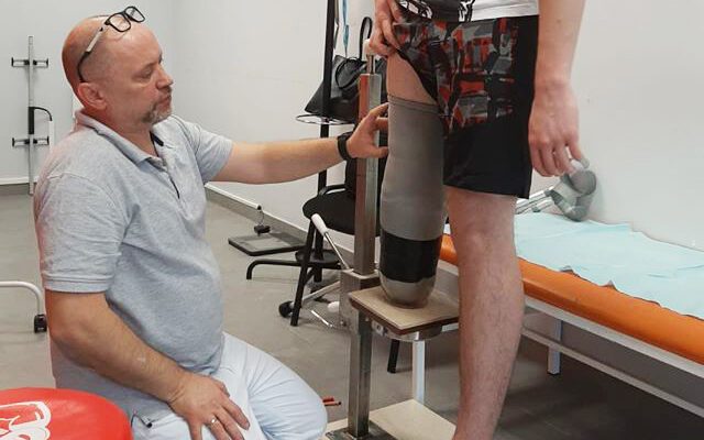 Mężczyzna siedzi na krześle z nogą w powietrzu.