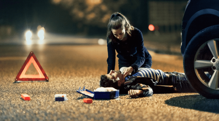 Mężczyzna leżący na ziemi obok samochodu.