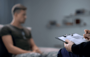 Mężczyzna siedzący na kanapie z schowkiem przed sobą.