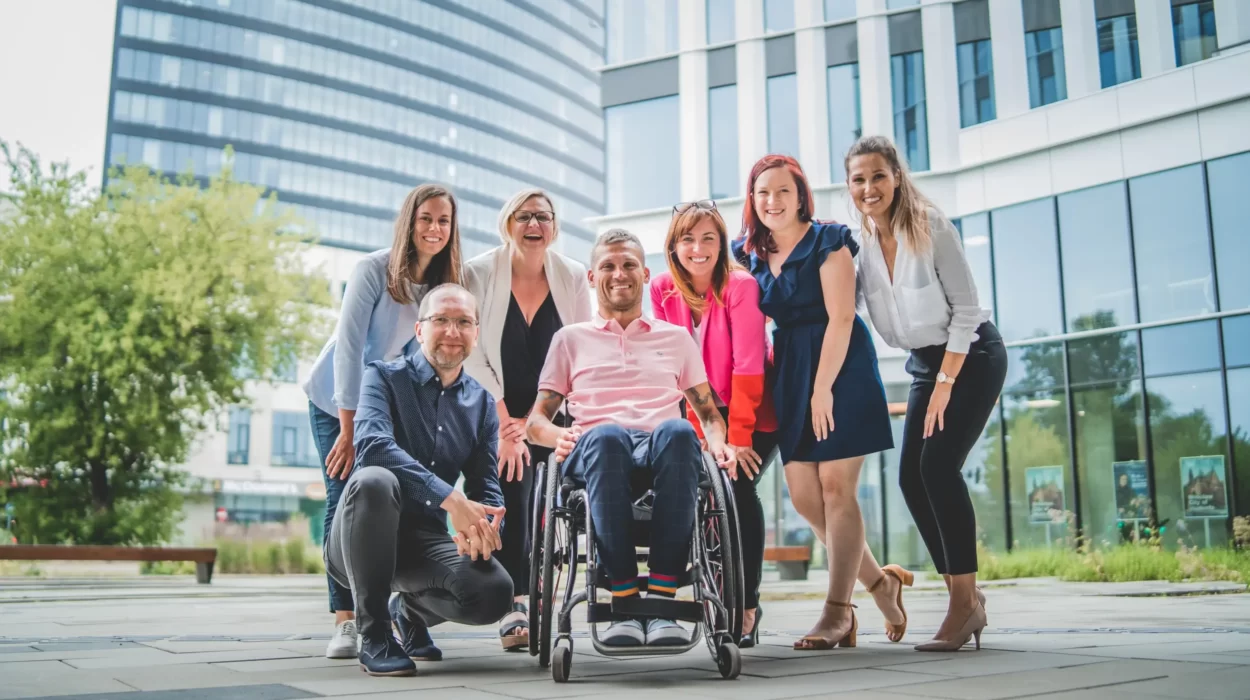 Grupa ludzi pozujących na zdjęcie z kobietą na wózku inwalidzkim.