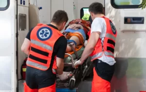 Zdjęcie ratownika medycznego ładującego pacjenta do karetki pogotowia.