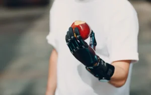 Osoba z robotycznym ramieniem trzymającym jabłko.