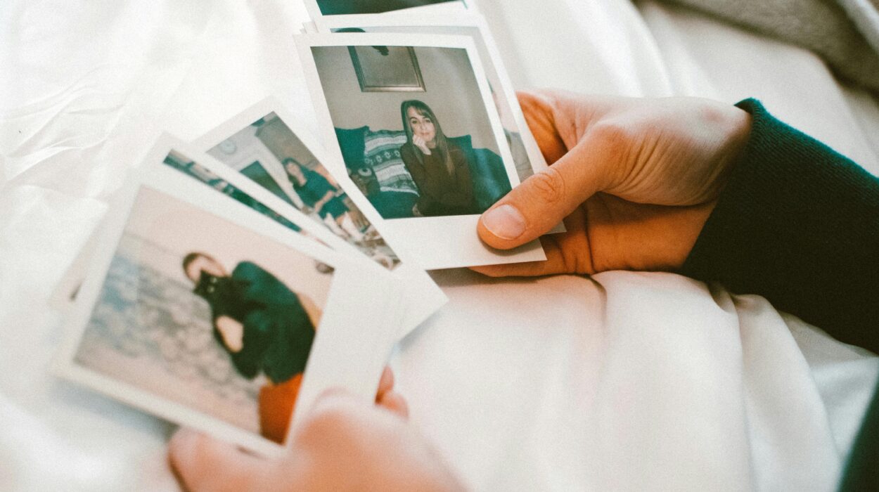 Osoba trzymająca Polaroidy na łóżku.